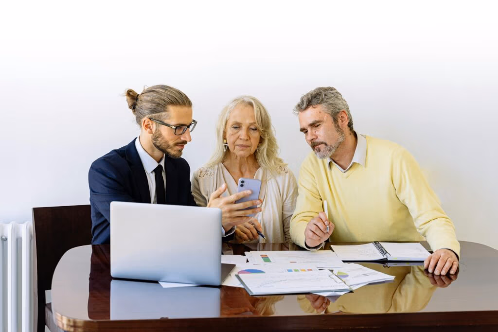 Frequently Asked Questions Three individuals collaborating on financial documents during a business meeting.